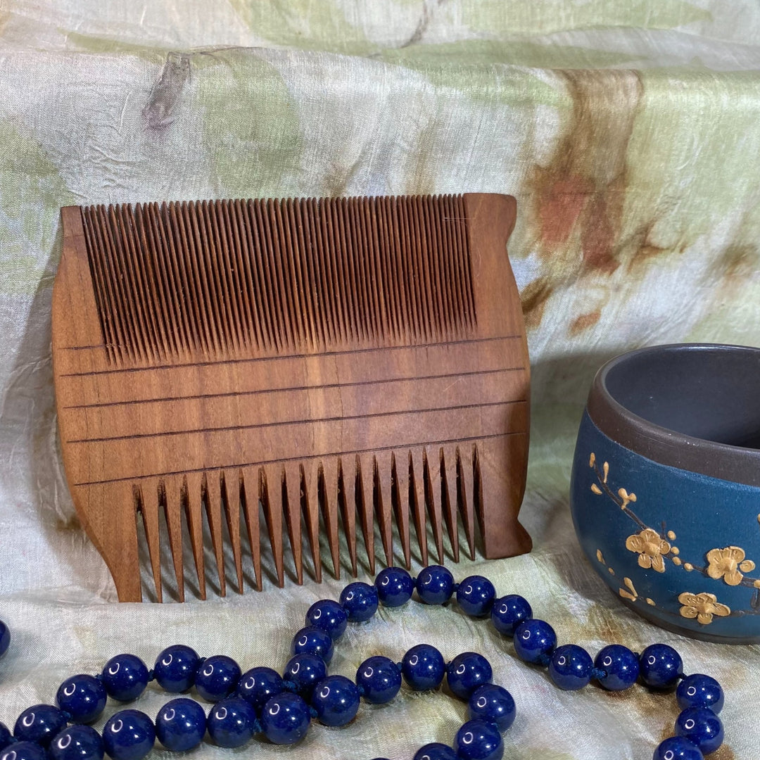 Large Hand-Carved Two-Sided Comb-Reproduction of Ancient Egyptian Comb-on Silk Background with Teacup and Blue Beads in Foreground