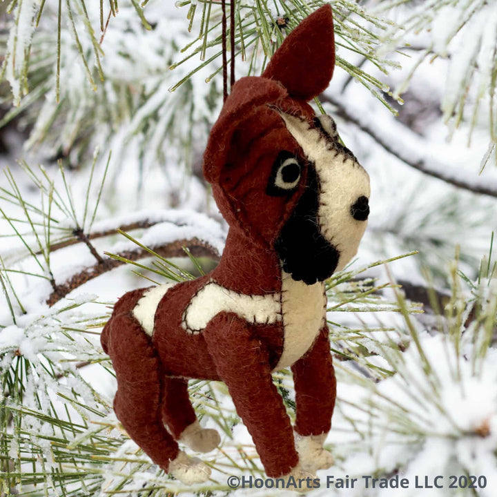 Brown and white felt boxer dog-handmade Christmas ornament, hanging from a snow-covered pine tree with long needles