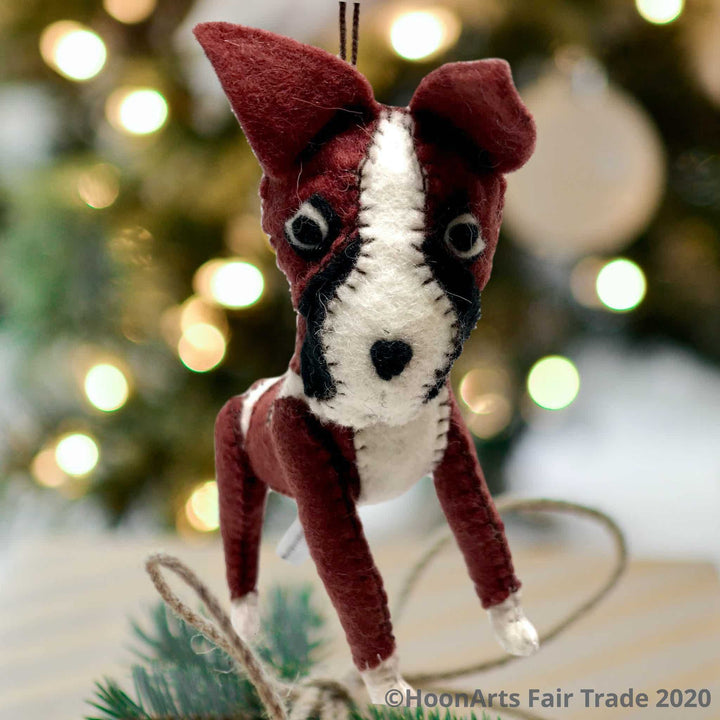 Felt Dog-Boxer, handmade Christmas ornament hanging against a background of white Christmas twinkle lights