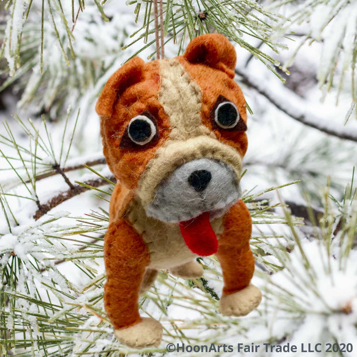 Adorable felt Christmas ornament- Tan and Beige bulldog with big eyes and red tongue hanging out, handing from long-needled pine tree covered in snow