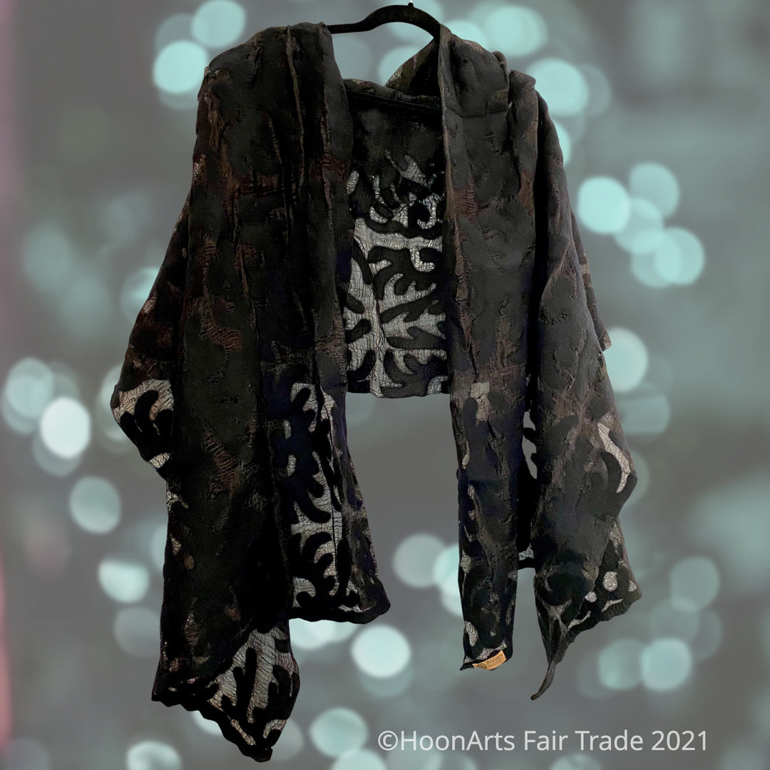 Handmade black sheer felted silk shawl, featuring traditional Kyrgyz eagle pattern, draped over coat rack | HoonArts