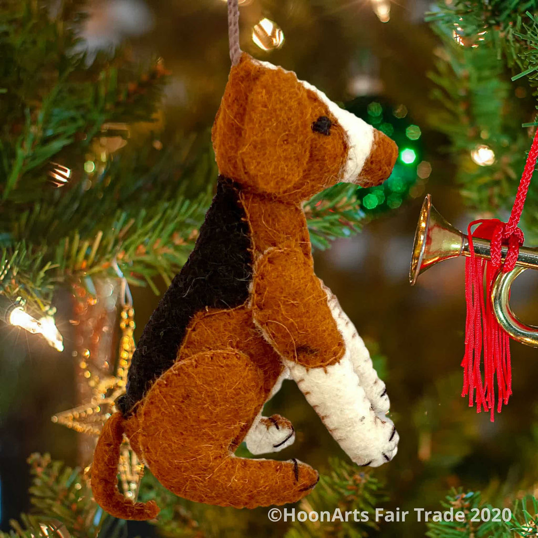 Handmade felt ornament from Kyrgyzstan-Beagle dog with black tan and white patches, seated on hind legs, hanging from a Christmas tree with brightly colored ornaments | HoonArts 