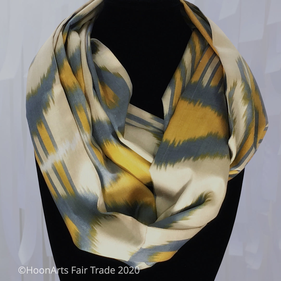 Handwoven Uzbek ikat infinity scarf in blue, yellow and cream, double-wrapped around black velvet necklace display stand