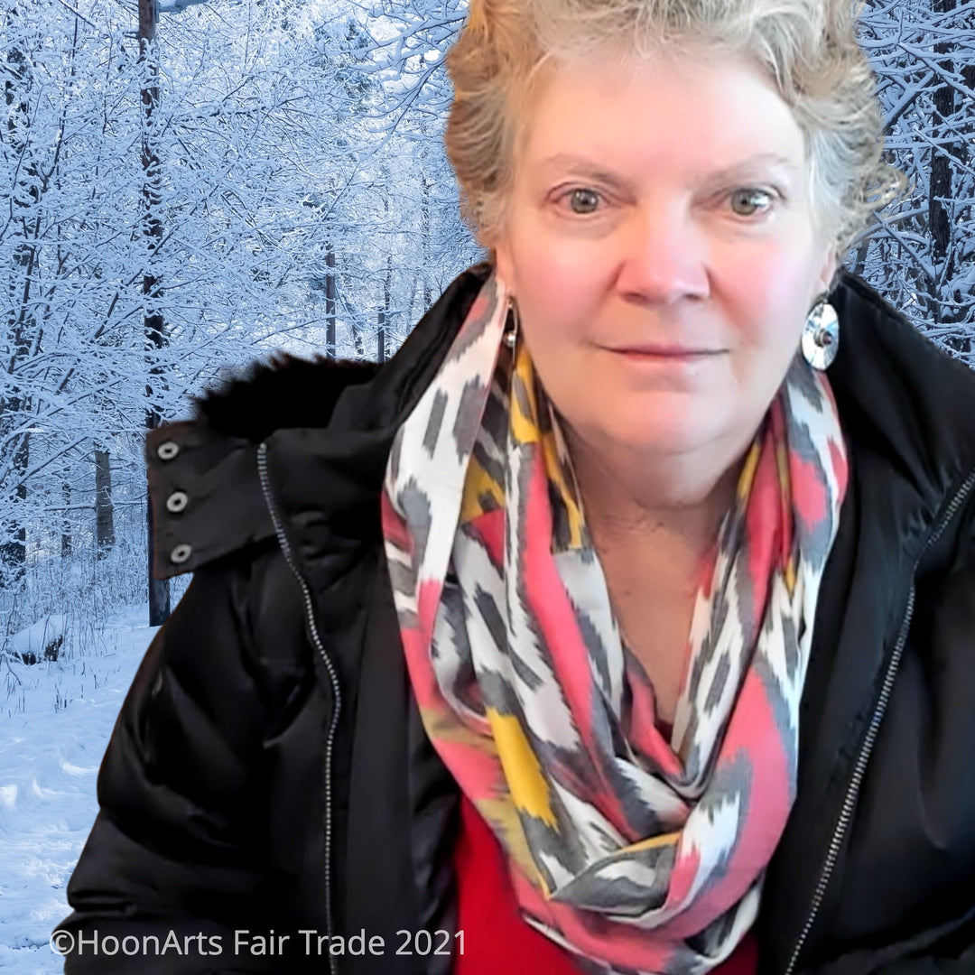 Red, white, Grey & yellow handwoven Uzbek silk ikat infinity scarf, worn by Caucasian woman in black coat, against snowy background