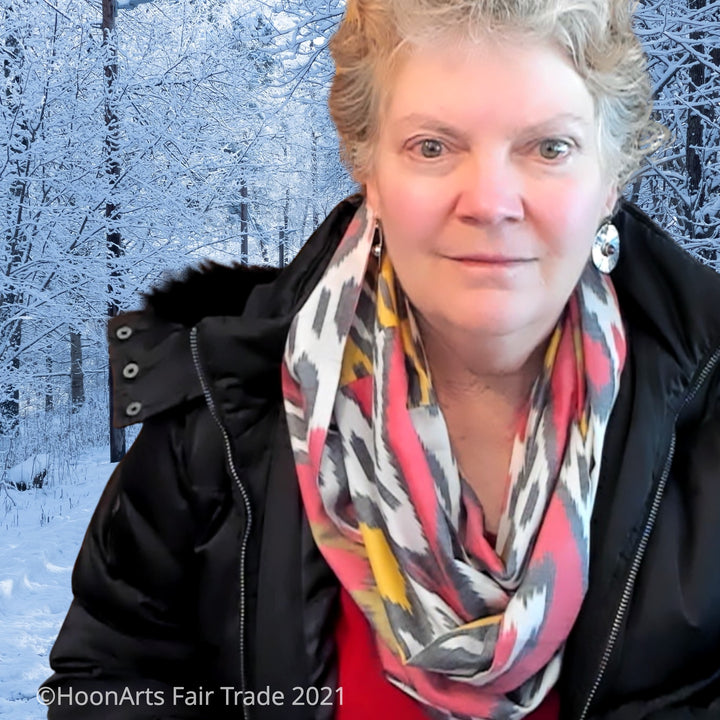 Red, white, Grey & yellow handwoven Uzbek silk ikat infinity scarf, worn by Caucasian woman in black coat, against snowy background