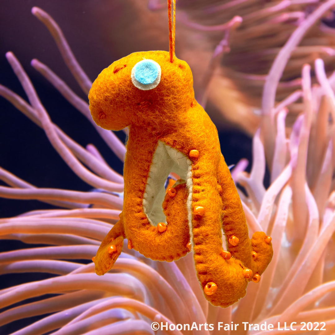Handmade Felt Ornament-Orange Octopus, with white underside, with orange iridescent beads dotting the orange upper side and bright eyes hovering over a sea coral