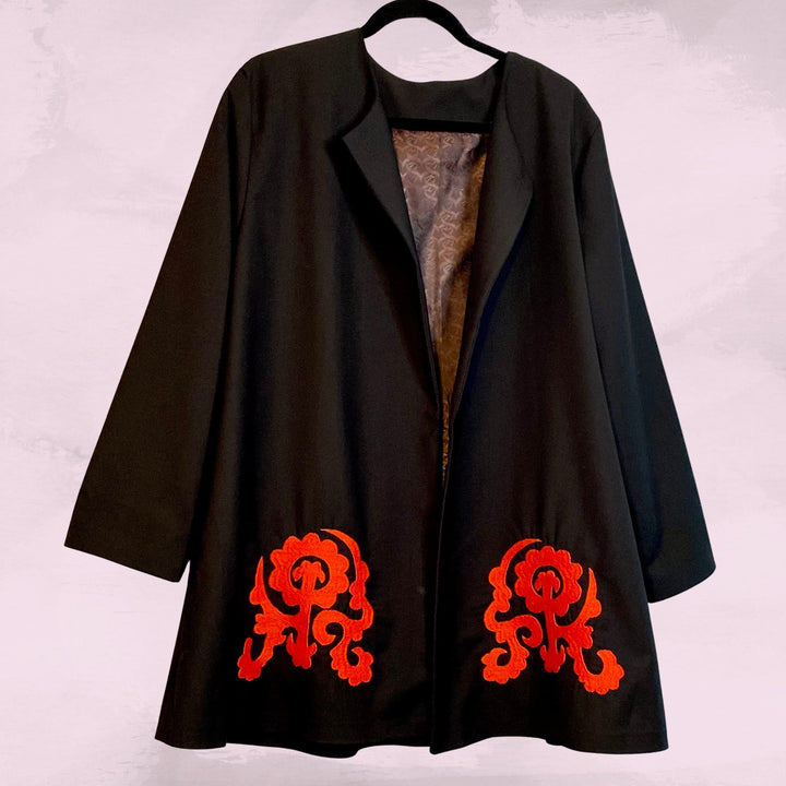 Black swing jacket on clothes hanger, showing front view and large red embroidery patterns at bottom front left and right