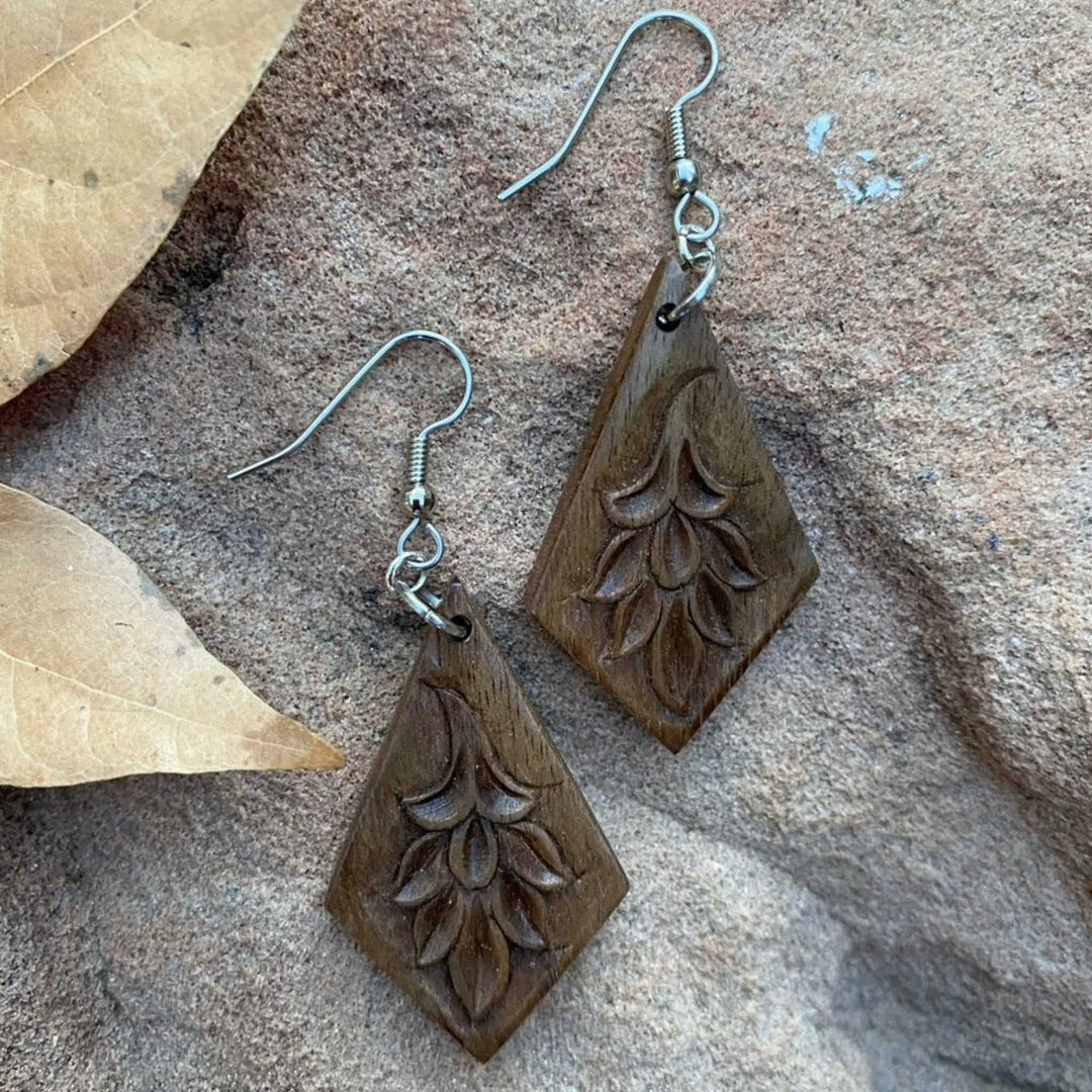 Handcarved walnut earrings in upside-down kite shape with floral patterns and surgical steel ear wires